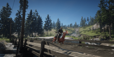 Player character riding a horse across a wooden bridge in a lush forest setting in Red Dead Redemption 2.